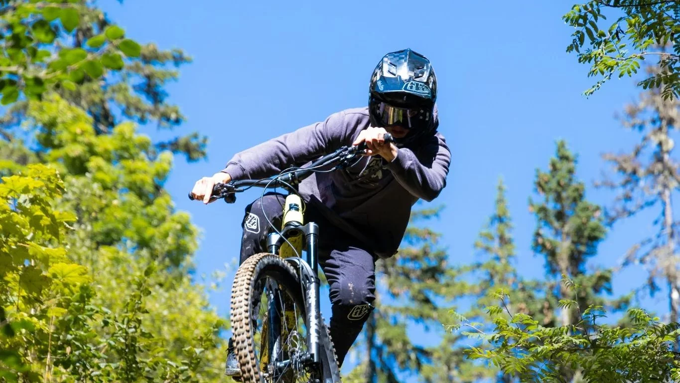 Un rider in mountain bike salta su un sentiero nel bosco
